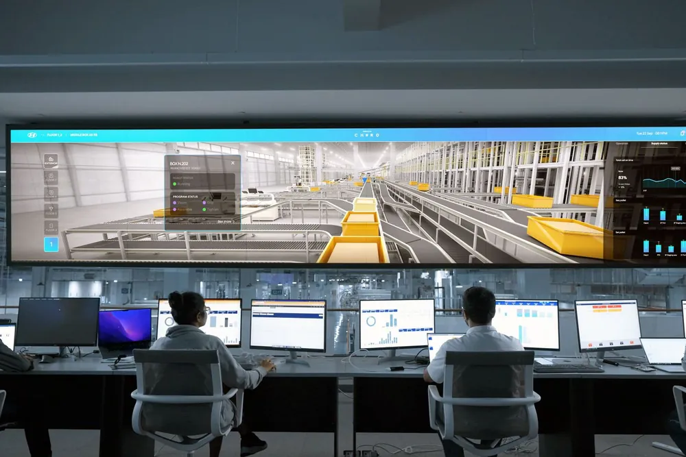 Equipe sentada diante de computadores em uma central de monitoramento, com um grande painel de imagens à frente